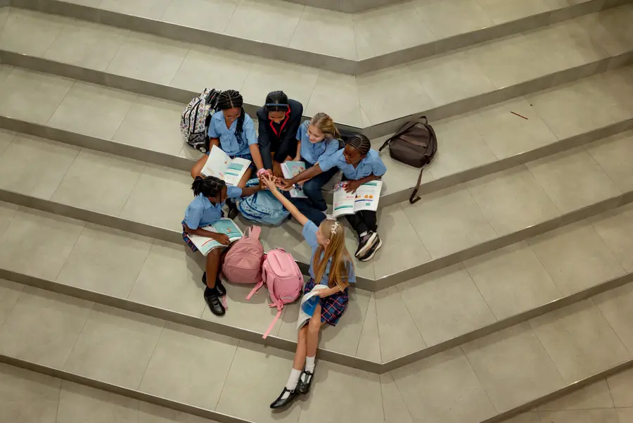 A group of children seen from above, sitting together on the steps with their books