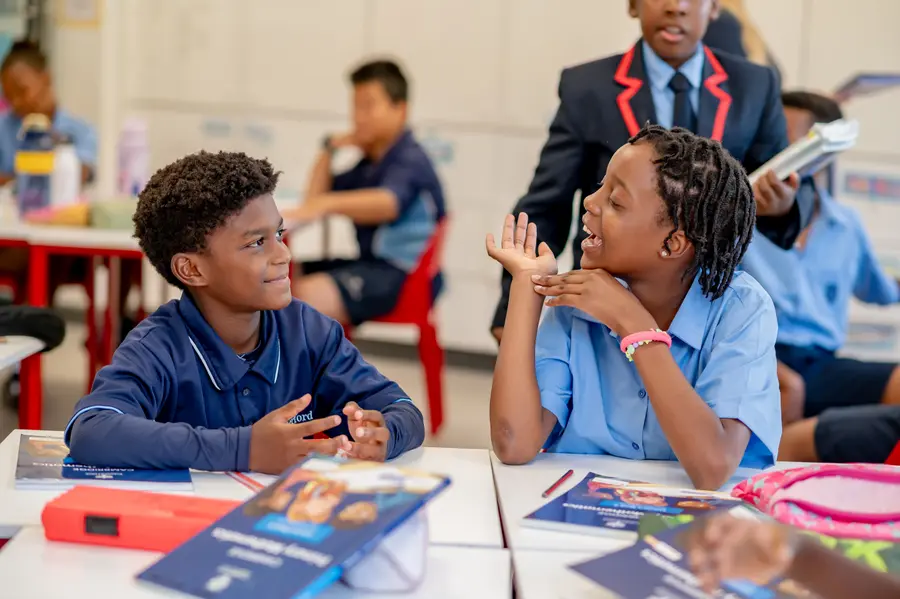 Two Preparatory School children laughing together over their books