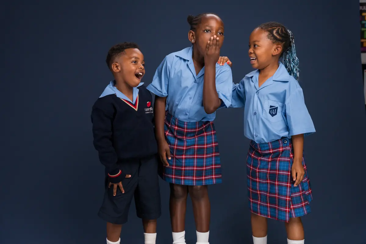 Three Preparatory School children laughing together in uniform
