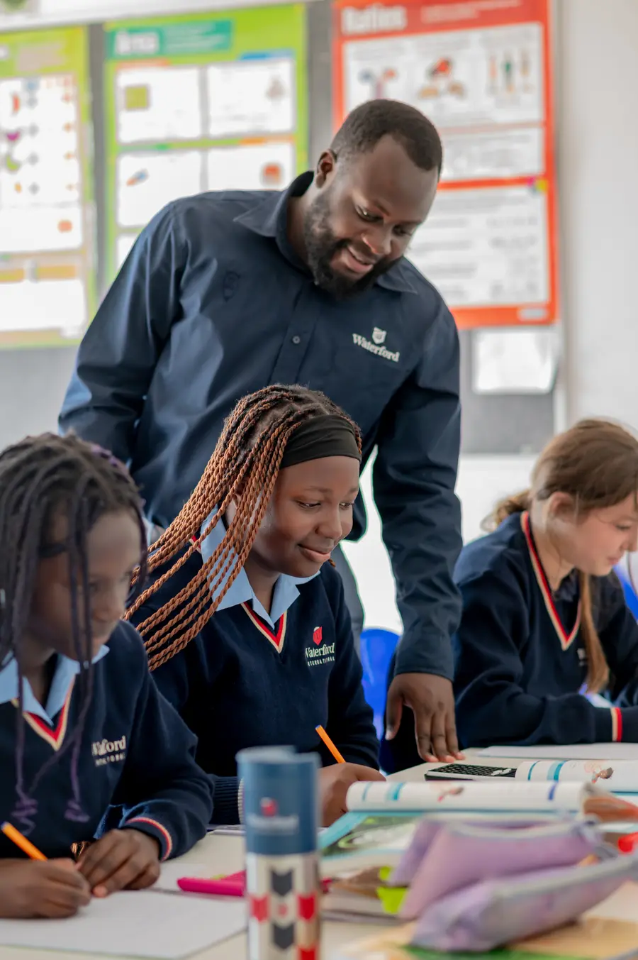 A teacher leaning in to help a small group of children at their desks