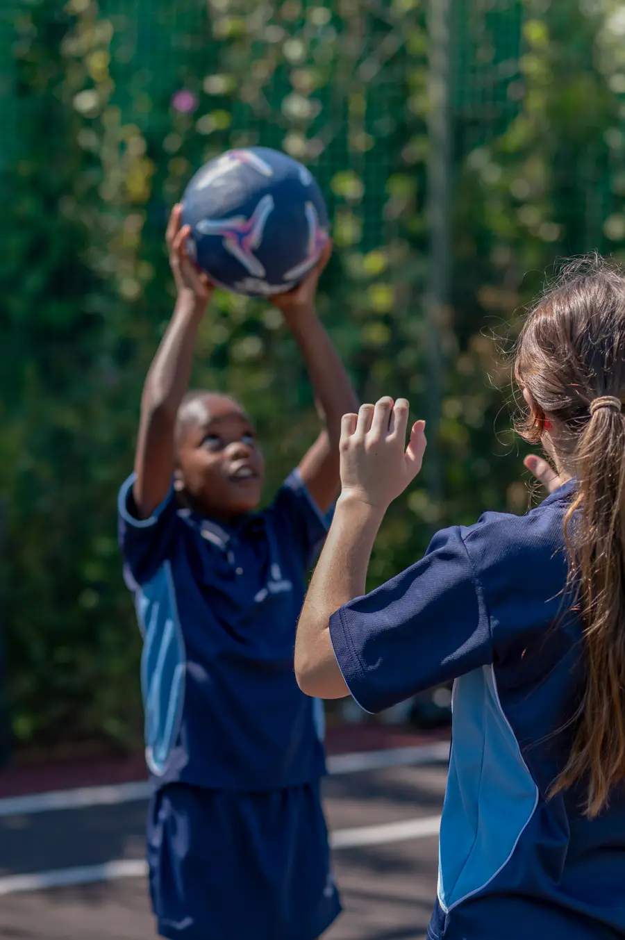 Two girls reaching for a netball at practice